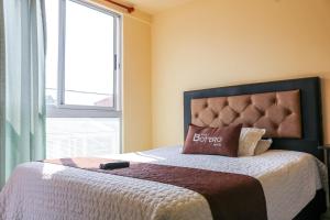 Schlafzimmer mit einem Bett mit einem Kissen und einem Fenster in der Unterkunft Hotel Casa Botero 305 in Bogotá