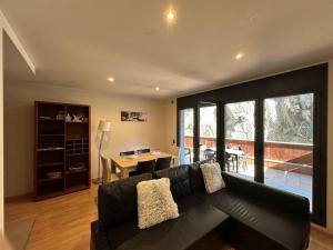uma sala de estar com um sofá preto e uma mesa em Apartament La Solana del Tarter 5p - El Tarter - Zona Grandvalira em Sant Pere