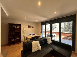 a living room with a black couch and a table at Apartament La Solana del Tarter 5p - El Tarter - Zona Grandvalira in Sant Pere