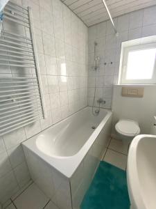 a white bathroom with a tub and a toilet at Zentrale 4-Zimmer-Wohnung in Sirnach in Sirnach