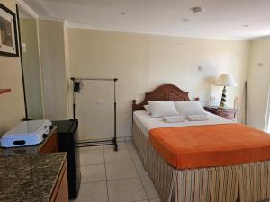 a bedroom with a large bed with an orange blanket at Maria Mulata Apartments in Noord