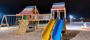 a playground with a slide on the beach at night at Blumar El Sokhna Chalet in Ain Sokhna