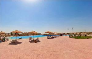 a beach with chairs and umbrellas and a swimming pool at Blumar El Sokhna Chalet in Ain Sokhna