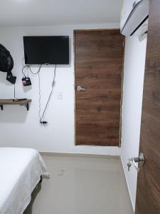 a bedroom with a bed and a television on a wall at HOTEL DI MAR in Cartagena de Indias