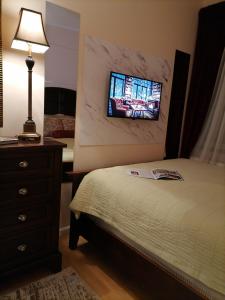 a bedroom with a bed with a tv on the wall at Harmony downtown apartment in Šabac