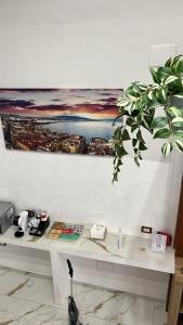 einen Tisch mit einer Pflanze an der Wand mit einem Gemälde in der Unterkunft San Ciro's Suite in Portici