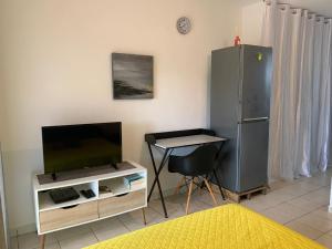 Habitación con TV, mesa y silla. en Le nid du Kikiwi , refuge relaxant avec jardin en Cayenne