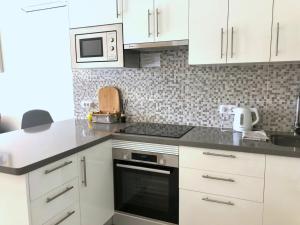 uma cozinha com armários brancos e um forno com placa de fogão em Apartamento de lujo en Torre del Sol, Playa de las Américas em Arona