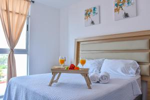 a bed with a tray of fruit and two glasses of wine at Volcano Views Apartment in San Salvador