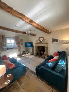 a living room with two blue couches and a fireplace at Bents Holiday Cottage in Oxenhope