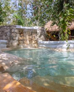 una piscina de agua con una pared de piedra en Eco Domos los Jaguares en Puerto Morelos