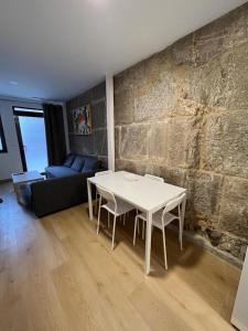 sala de estar con mesa blanca y pared de piedra en Apartamento Baixo da Barbeira, en Cangas de Morrazo