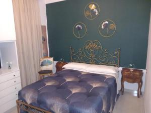 Un dormitorio con una cama y una pared verde. en Geena's Home, en La Spezia
