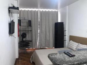 a bedroom with a bed and a television and a window at STUDIO IPANEMA CONFORTÁVEL in Rio de Janeiro