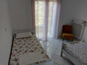 um quarto com duas camas, uma cadeira e uma janela em Marilena Apartments Plataria em Plataria