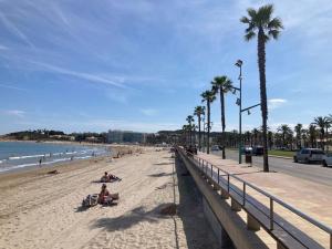 a beach with people laying on the sand and palm trees at Piso centro Salou cerca mar in Salou