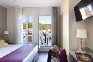 een hotelkamer met een bed en een glazen schuifdeur bij Best Western Hotel du Roy d'Aragon in Bonifacio