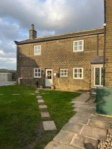 una casa de ladrillo con un patio de hierba delante de ella en Bents Holiday Cottage en Oxenhope