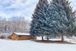 a cabin in the snow next to a tree at Riverfront Paradise - Entire Home in Gypsum