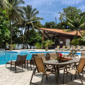 a patio with a table and chairs next to a pool at Aninga Lodge in Tortuguero