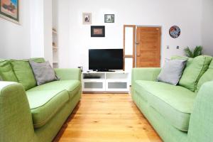 een woonkamer met twee groene banken en een televisie bij Stylish modern 1 bedroom property in Greenwich! in Londen