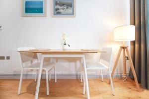 een eettafel met witte stoelen en een lamp bij Stylish modern 1 bedroom property in Greenwich! in Londen