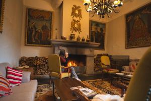 a woman sitting in a living room with a fireplace at Casa Andina Premium Cusco in Cusco