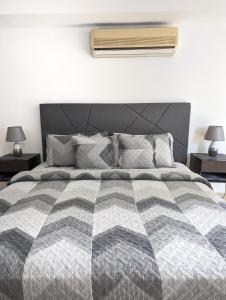 1 dormitorio con 1 cama con edredón gris y blanco en Yc l Habitacion av Balboa - GB2301-B en Panamá
