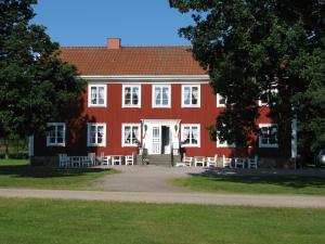 uma casa vermelha com janelas brancas e cadeiras em frente em Södra Ljunga Vandrarhem em Ljungby