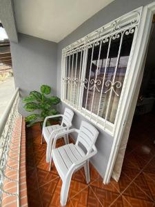 2 sillas blancas y una mesa en el balcón en Apartamento acogedor en la Union, Valle del Cauca en Lemos