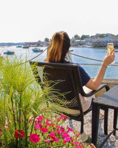 a woman sitting in a chair taking a picture of the water at Boothbay Harbor Inn in Boothbay Harbor