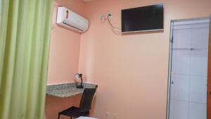 a room with a television on the wall and a chair at Hotel Goiânia Executive in Goiânia