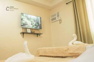 um quarto com televisão e cisnes numa cama em Cozy Studio Unit at Persimmon em Cebu