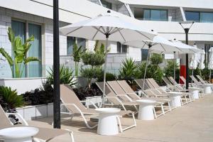 a row of tables and chairs with white umbrellas at סוויטות עם נוף וצמודות לים במתחם SeaSide היוקרתי עם בריכה - By SEAELO EILAT in Eilat