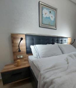 a bed with a blue headboard and a table with a lamp at Chabili Appartements in Temara