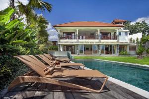 a villa with a swimming pool and two lounge chairs at Villa Yenian in Canggu