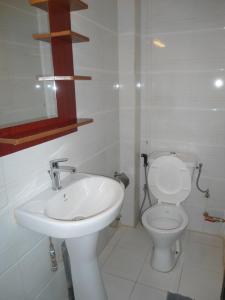 La salle de bains blanche est pourvue de toilettes et d'un lavabo. dans l'établissement Daaru Jamm, à Dakar