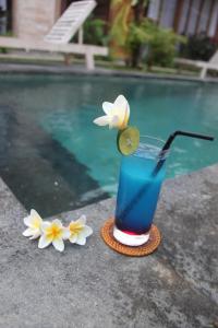 a drink with a flower on a coaster next to a pool at Umaya Ubud Villa in Ubud