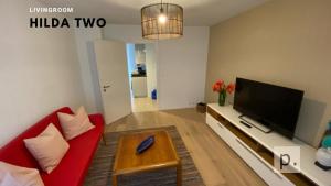 sala de estar con sofá rojo y TV de pantalla plana en H2 with 3,5 rooms, 2BR, living room and kitchen, central and quite en Zúrich
