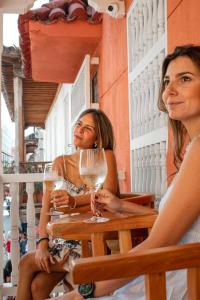 Dos mujeres sentadas en una mesa con copas de vino en Casa Noa Colonial Rooms By SOHO en Cartagena de Indias