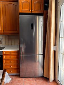 a stainless steel refrigerator in a kitchen with wooden cabinets at Cozy Apartment Katerini in Katerini