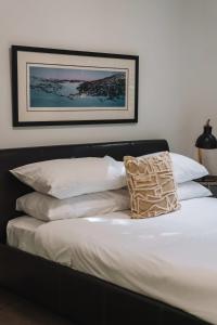 een bed met witte kussens en een foto aan de muur bij Comfy 1-Bed with Spacious Courtyard & Parking in Phillip