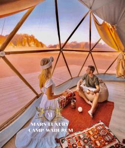 a man and a woman sitting inside a tent at MARS lUXURY CAMP WADI RUM in Wadi Rum