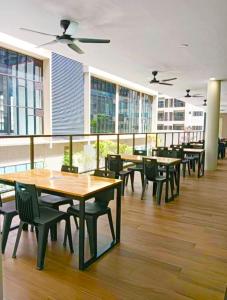 a cafeteria with wooden tables and chairs and windows at Youth City 2 Bedroom Pool View by DKAY in Nilai in Nilai