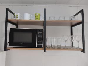 un microondas en un estante con copas de vino en My House Hospedagem, en Santo Ângelo