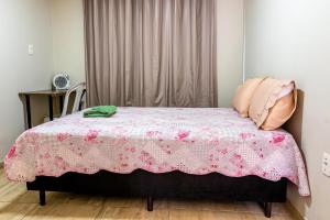 um quarto com uma cama com um cobertor rosa em Apartamento próximo centro em Lages