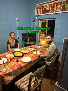 a group of people sitting around a table with food at Catch The Ella Train Hostel in Kandy