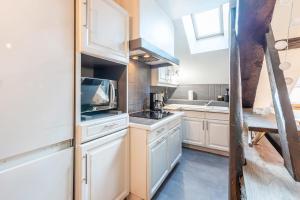 a kitchen with white cabinets and a sink at LE PAQUIER T3 - à deux pas du lac in Annecy