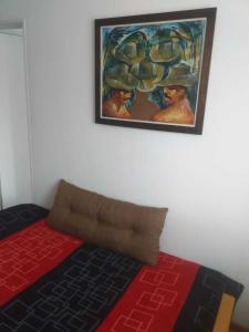 a painting hanging on a wall above a bed at Cómodo Departamento Hogareño in San Carlos de Bariloche