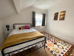 a bedroom with a bed and a rug at 4-Bedroom home - Perfect for those working in Bridgend - By Tailored Accommodation in Bridgend